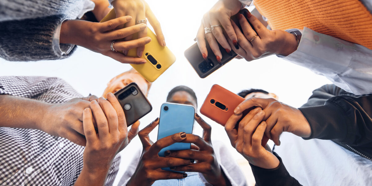 Multiple teens in circle holding smart phones