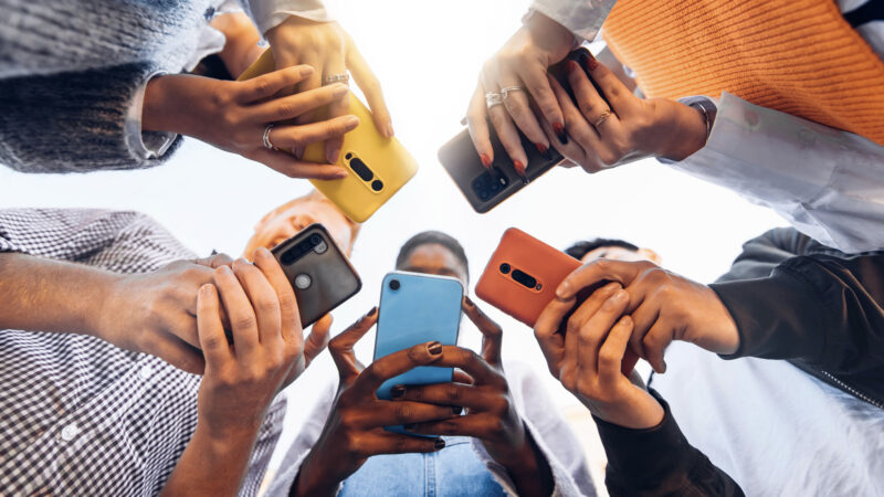 Multiple teens in circle holding smart phones