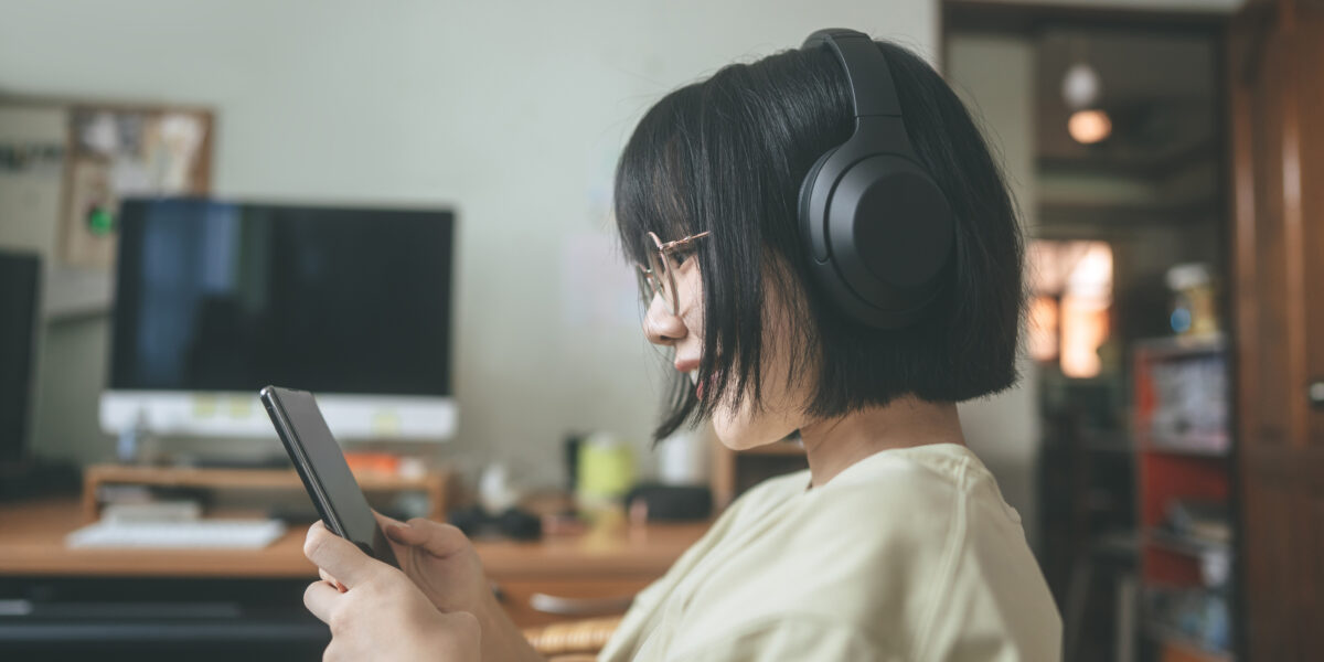 Young woman wearing headphones listening to music and relaxing while watching her smartphone