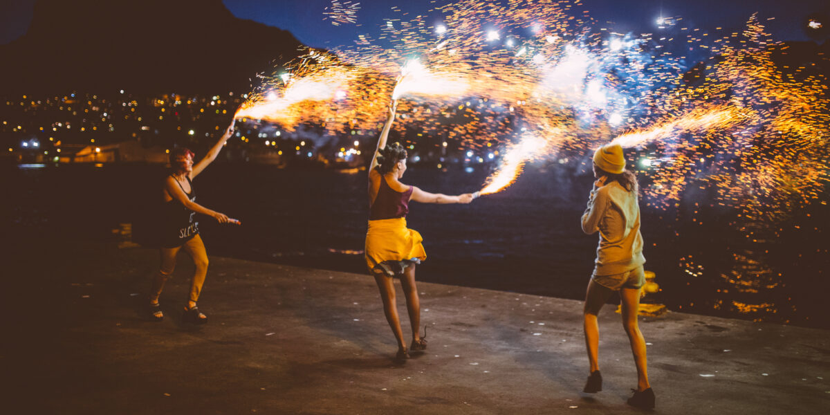 Girls dancing with firework flares at night