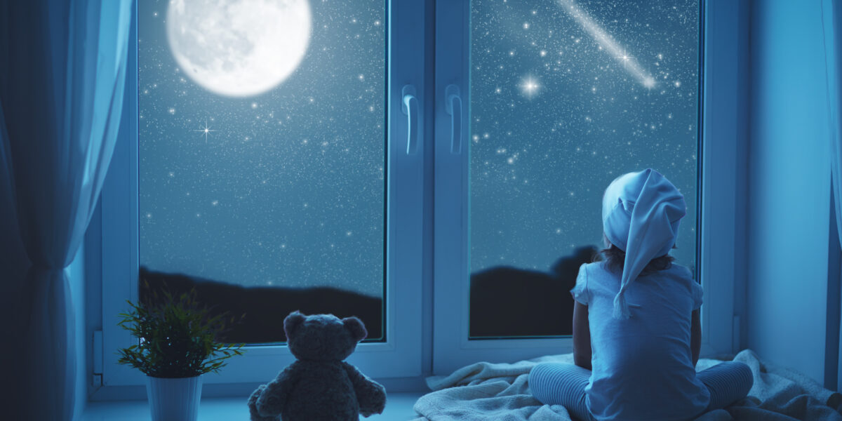 Little girl at window dreaming and admiring starry sky