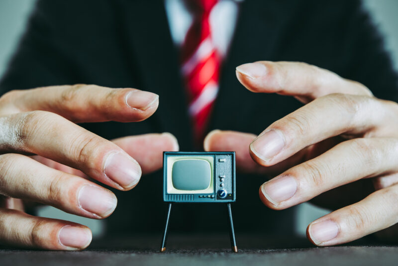 Business man holding a tiny television