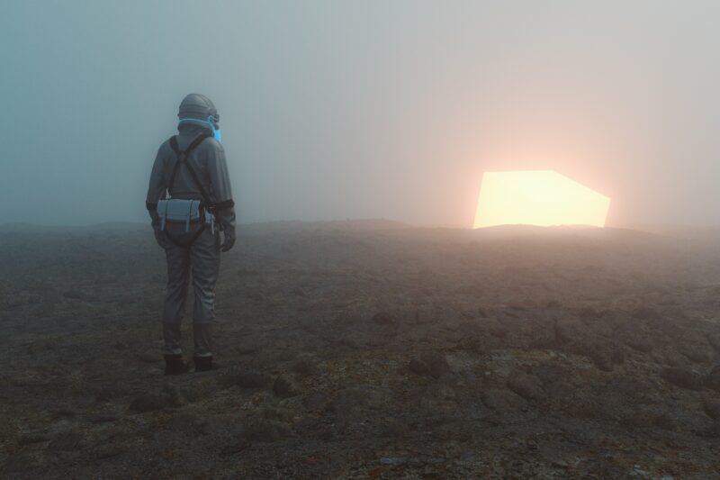 Sole person walking towards the light in a desert wearing a protective suit